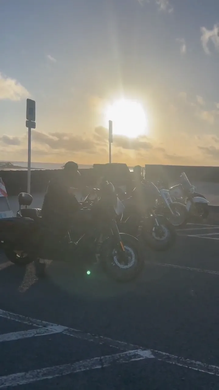 逆光の駐車場に並ぶバイクとメンバーの映像
